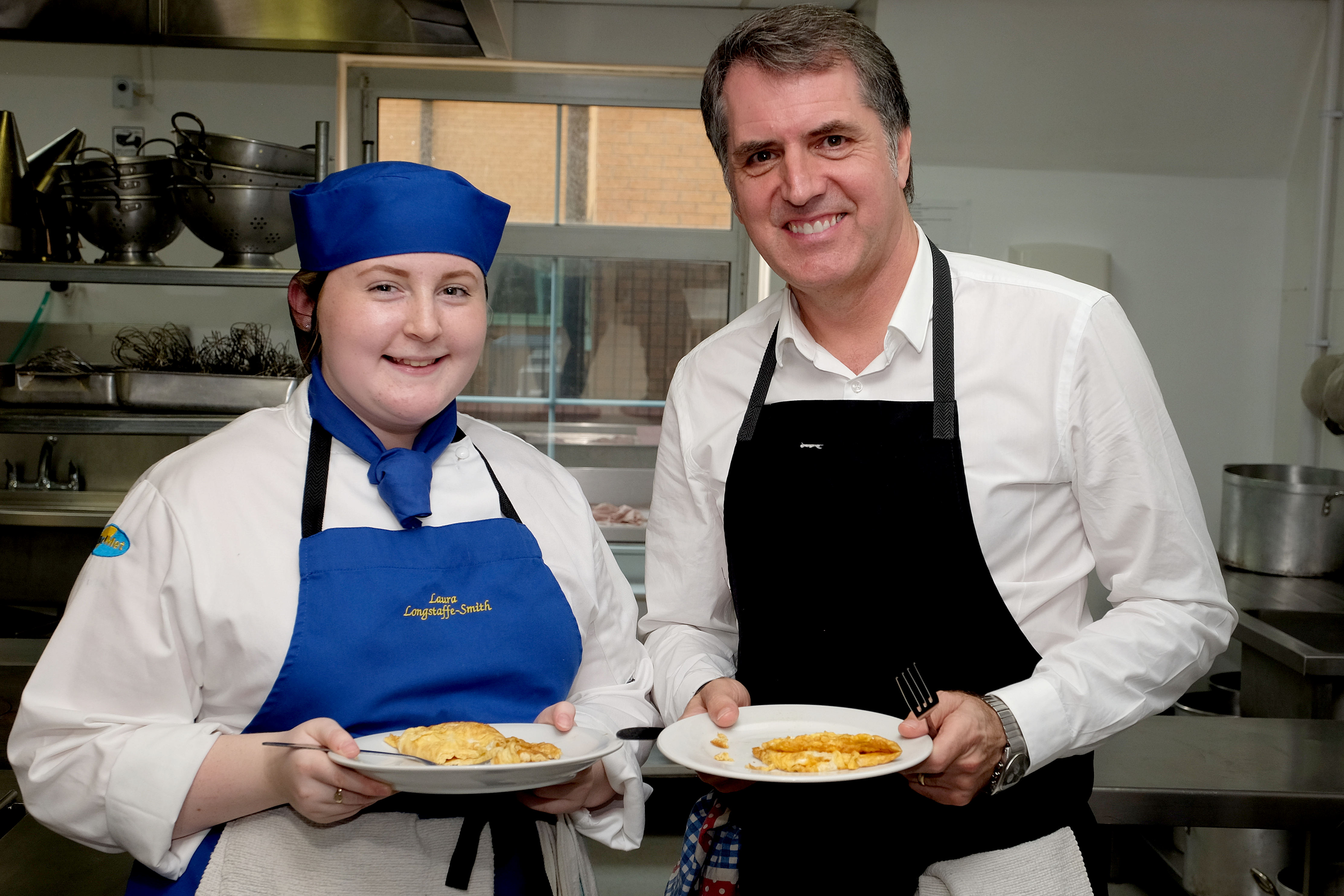 Metro Mayor Steve Rotheram standing next to a Wirral Met Hospitality and Catering students holding a plate of food