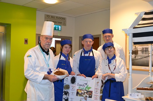 Wirral Met Hospitality and Catering students standing next to a tutor holding a sign that says 'crunchy critters' during Visitor Economy Week