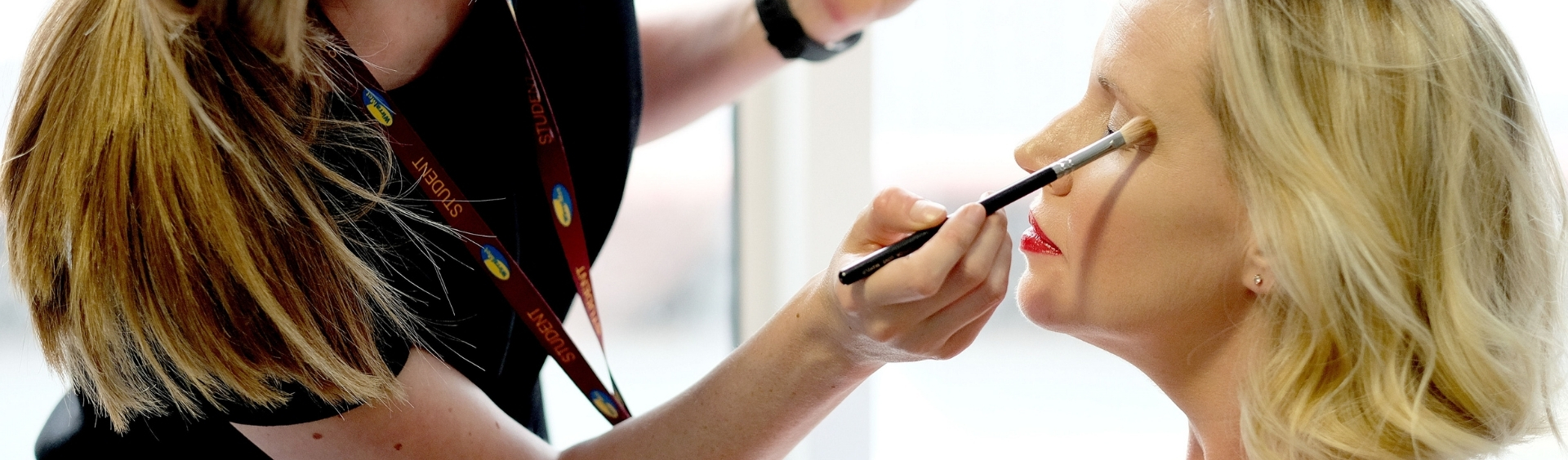 WMC Fashion and Photographic Make-Up student working on customer inside classroom