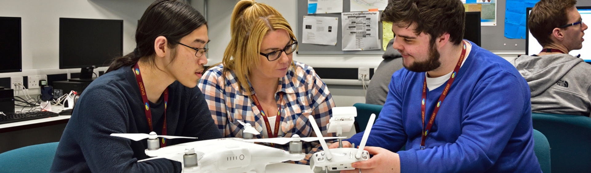 Three WMC Foundation Degree Computer Science students playing with drone in Computing classroom