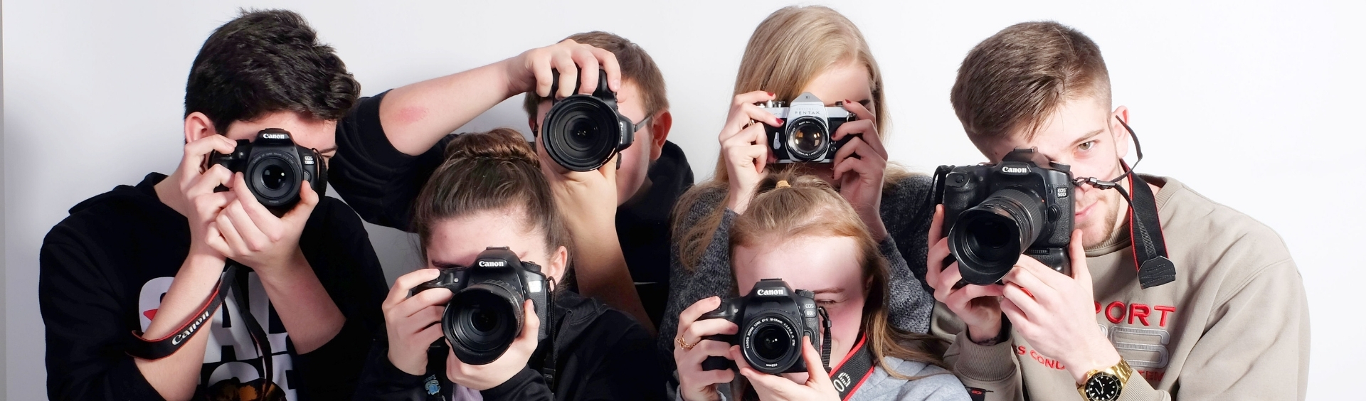 Wirral Met HND Photography students aiming cameras in front of a white background