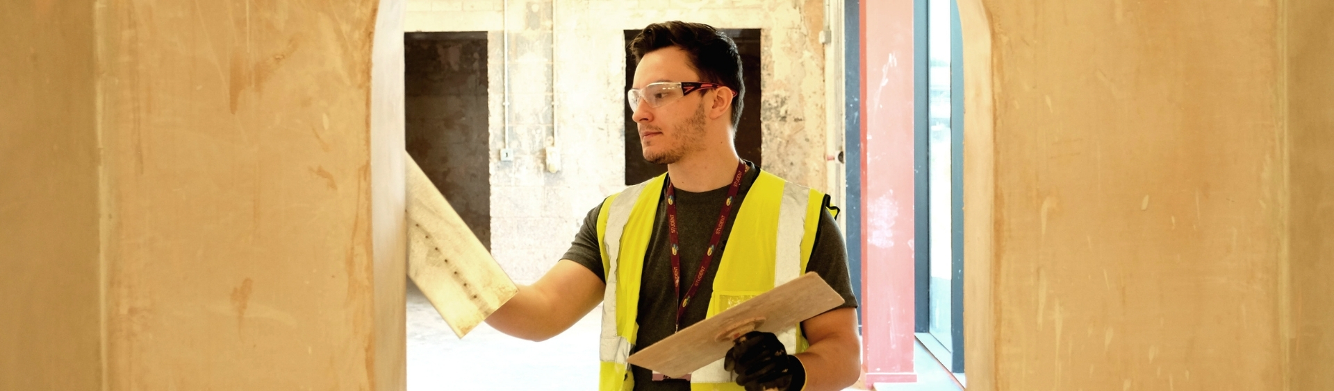 WMC Plastering student working on a wall inside building