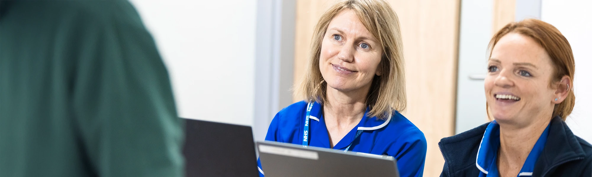 Two Women in NHS Uniforms sat at a laptop