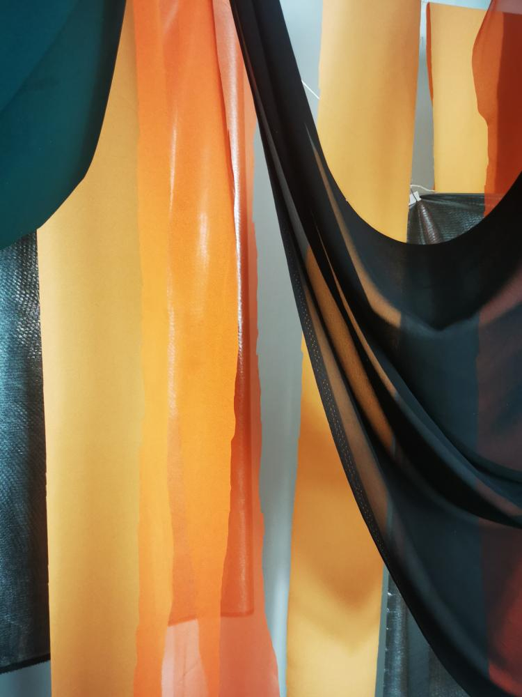 pieces of different coloured fabric draped from the ceiling 