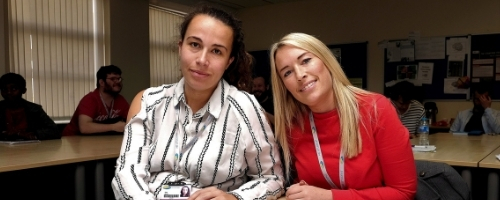 two female students sat at desk in classroom