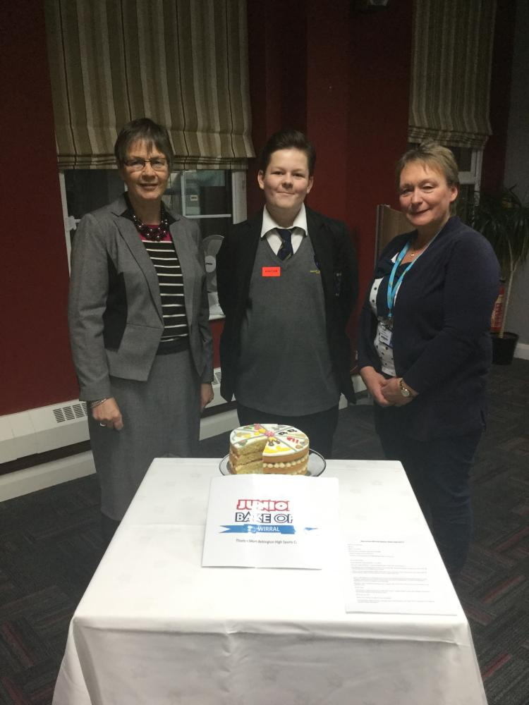 Winner of the Bake Off 2017 Thomas Mort from Bebington High School standing next to judges Lonna Tyson and Ada Williams above the winning cake named The Seven Wonders of the Wirral