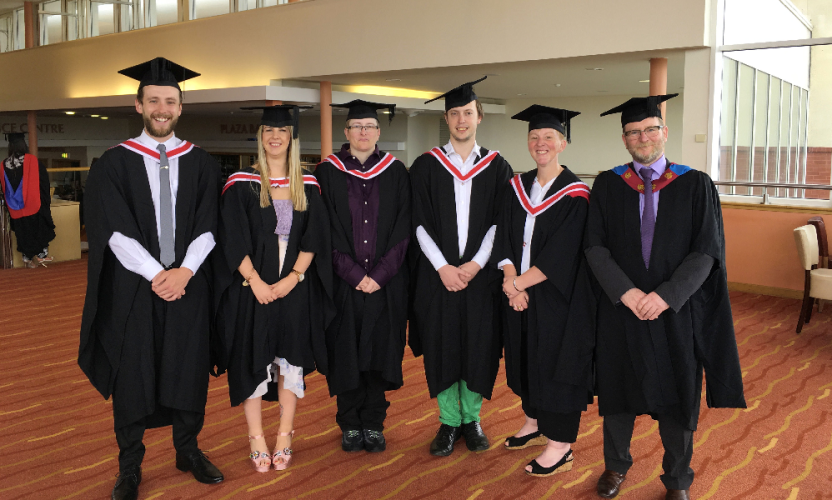 Wirral Met Higher Education graduates wearing gowns and standing in the Floral Pavillion