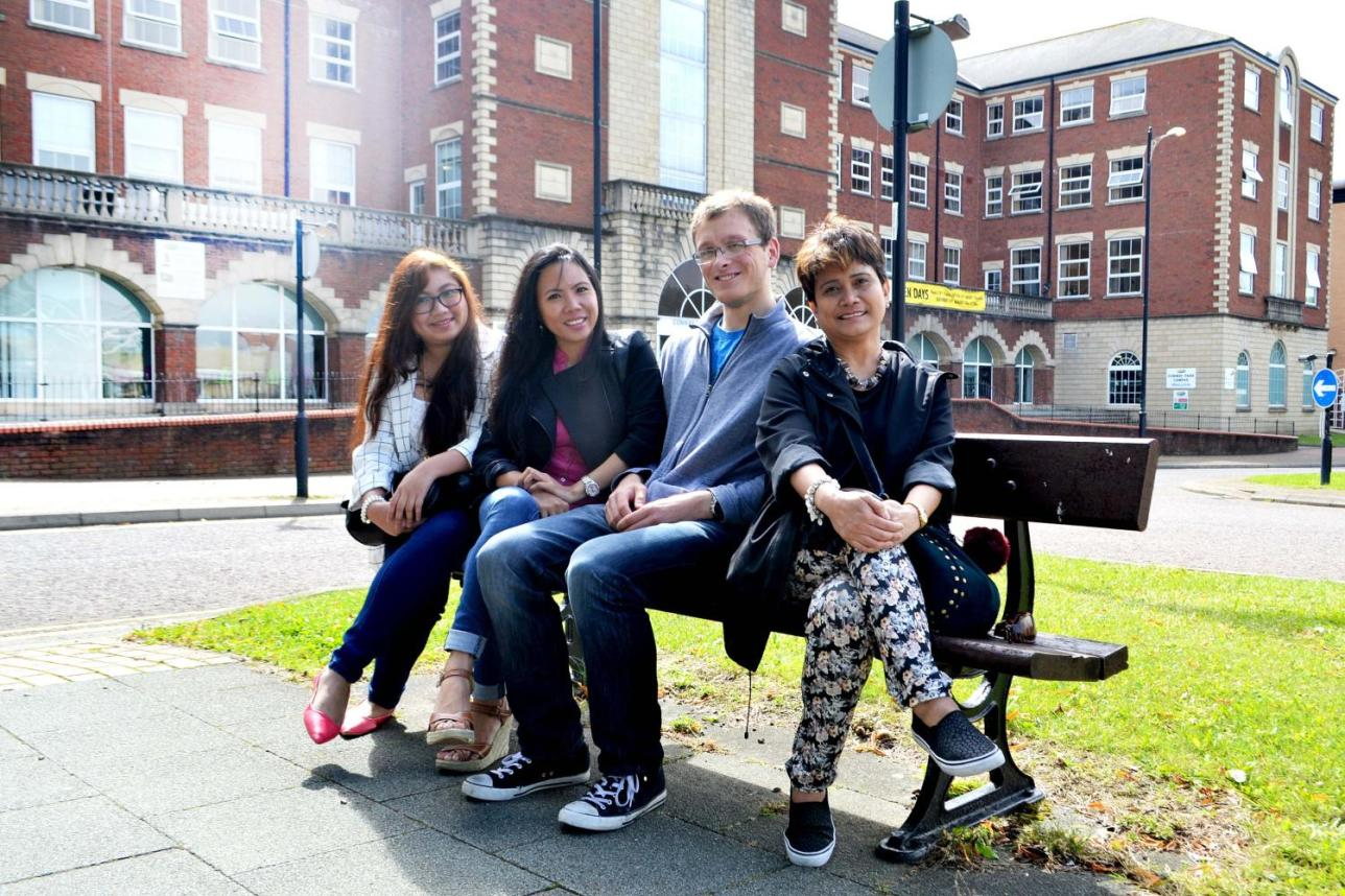 Four Wirral Met students sat on a bench outside the Conway Park campus