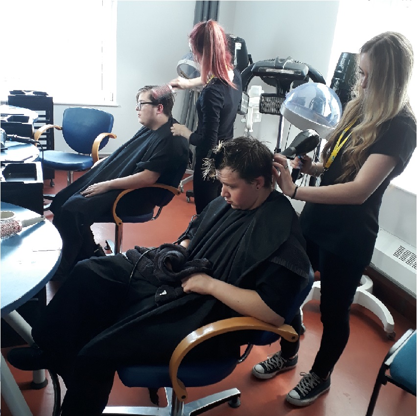 Wirral Met Hair and Beauty student wearing black blow drying hair