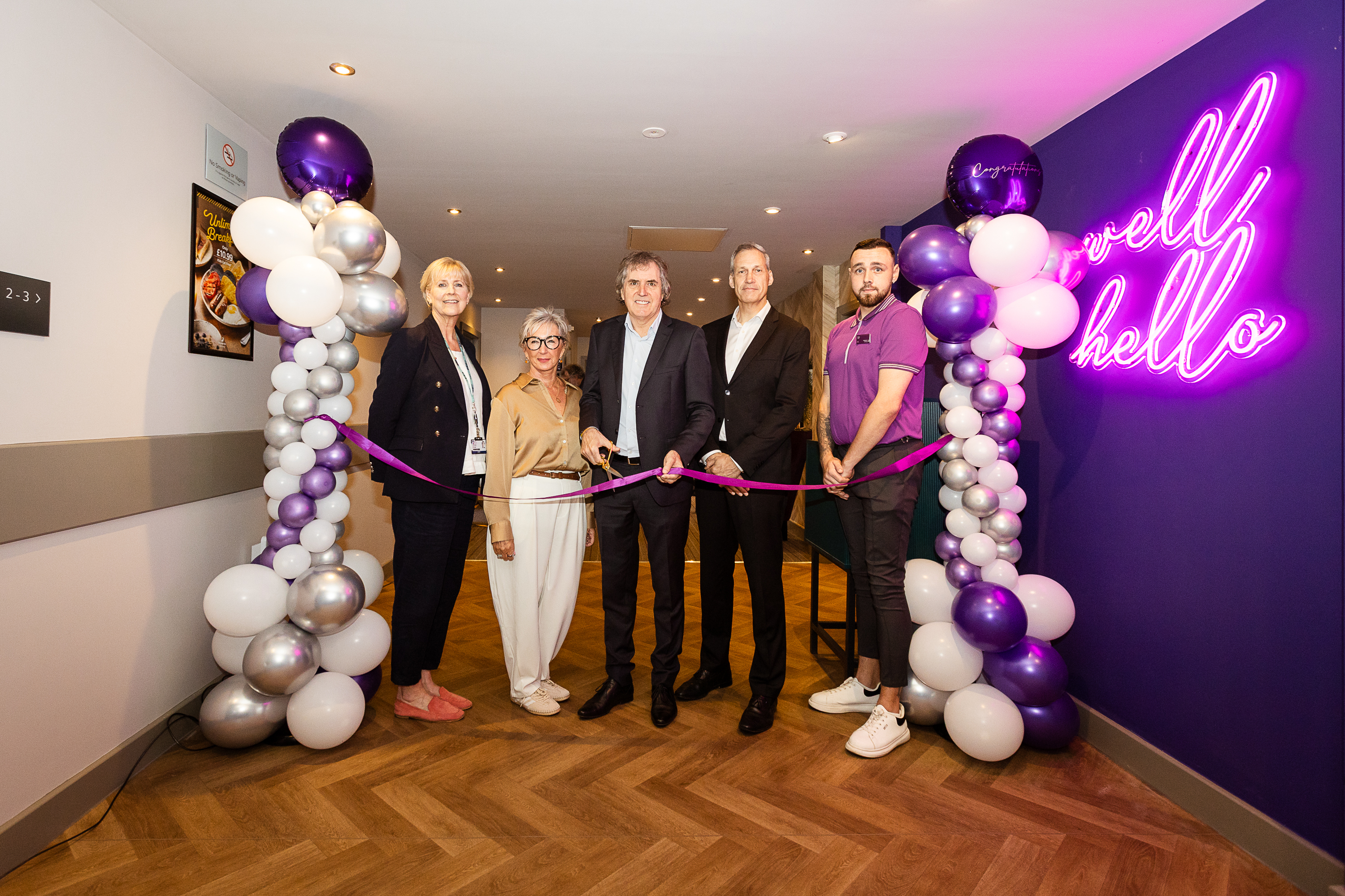 Four people, with the premier Inn and a purple ribbon. 