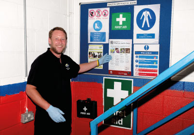 Male Health Safety And First Aid CPD Student Standing Next To First Aid Notice Board
