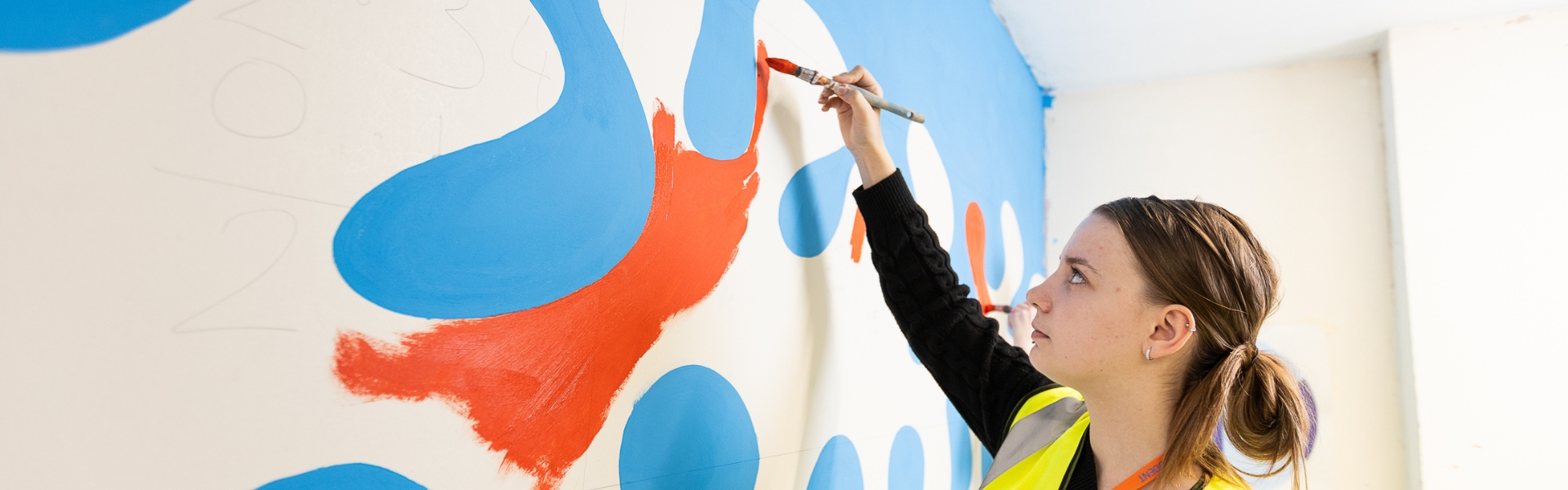 Paining and Decorating student painting a wall inside of a classroom in Wirral Waters
