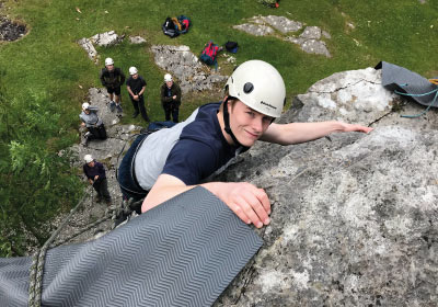 Public And Uniformed Services Students Climbing A Rock Outdoors