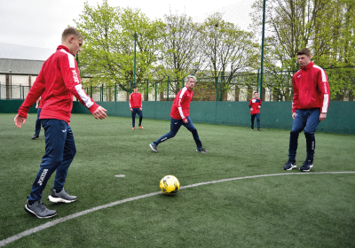 Wirral Met Sports, Fitness and Outdorr Education students playing football on an AstroTurf wearing red sport jackets