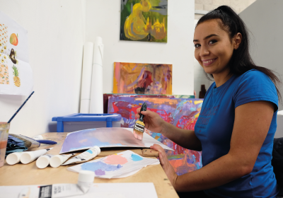 Female Art And Design Student Painting Inside Classroom