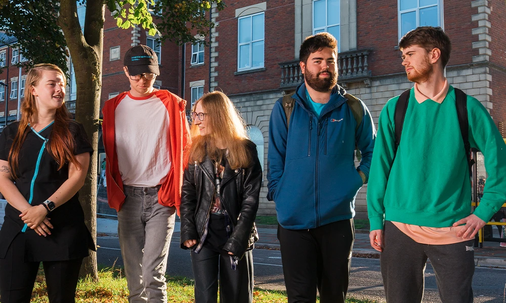 Five students walking on grass away from a building