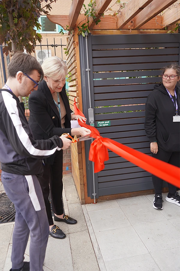 Male and female cutting a red ribbon