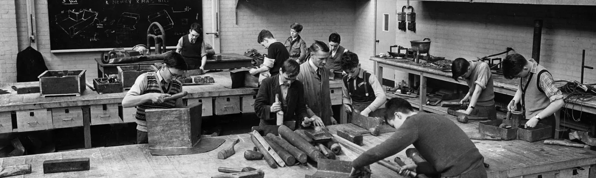 A black and white photo from when the college was first opened with men working in a workshop