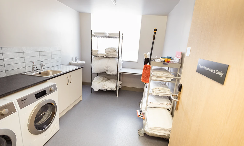 An laundry room with washing machines and a cleaning cart in