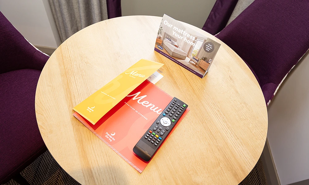 A red menu on a circular table with a tv remote