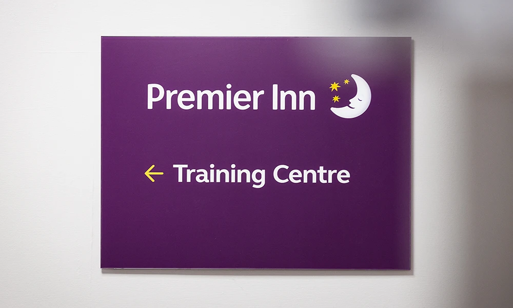 Purple Sign with the Premier Inn and training centre with an arrow pointing left
