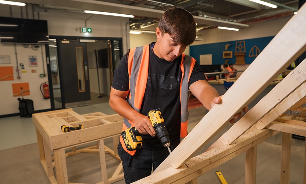 Carpentry and Joinery student sawing wood inside Wirral Waters workshop