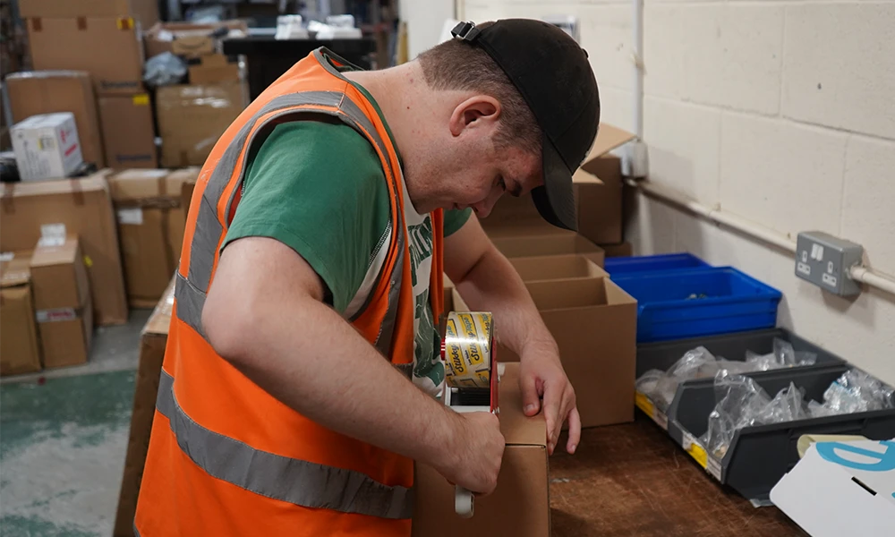 A student packing boxes in a warehouse