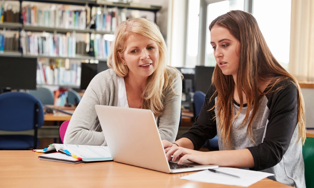 A mother and daughter sat on a laptop