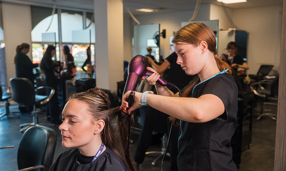 Beauty student doing makeup of another student inside classroom