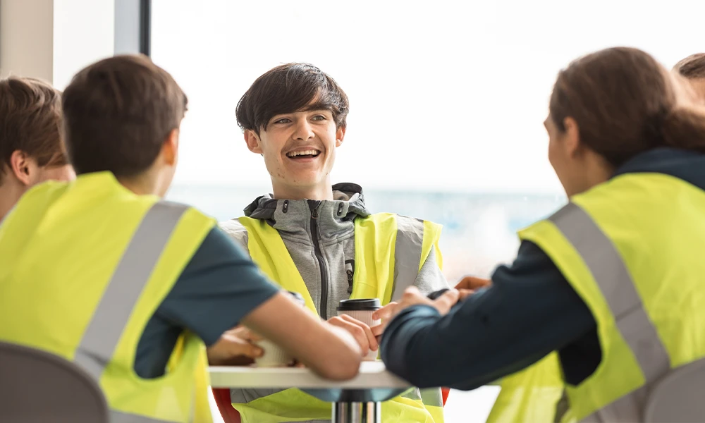 Males sat smiling directly at the camera in hivis