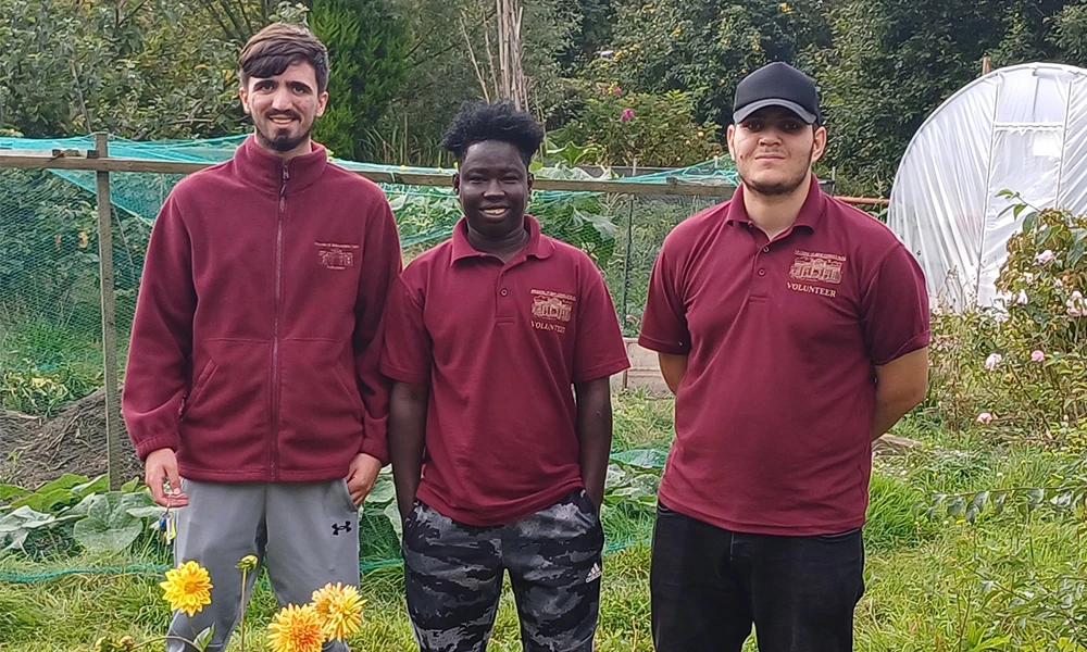 Three men stood in a field in burgundy clothes on