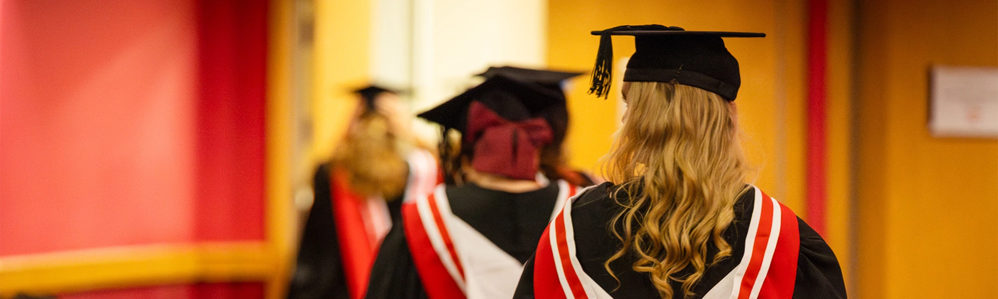 Three women in cap and gown walking away from the camera