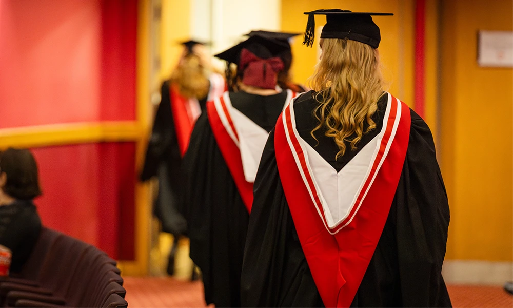 Three women in cap and gown walking away