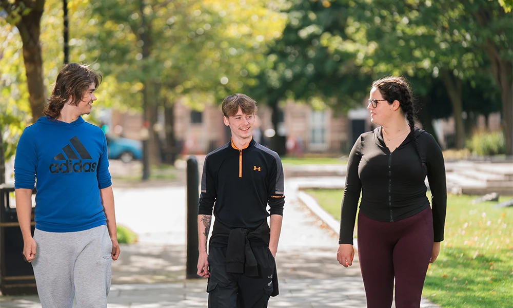 Three Wirral Met students talking to each other whilst walking through Hamilton Square