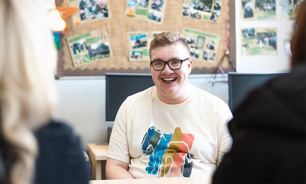 Progression into Further Education student sitting inside classroom smiling