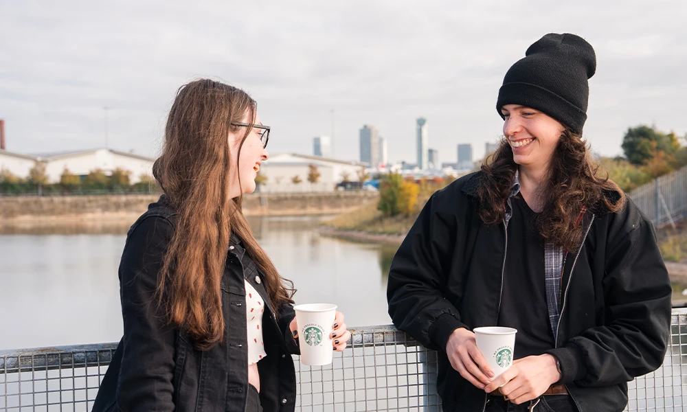 Two people leaning on railings smiling