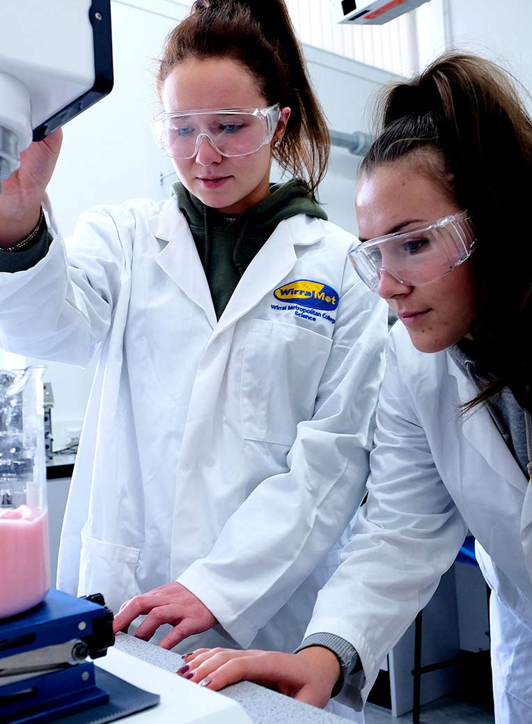 Wirral Met Science students wearing safety glasses and looking down at an experiment