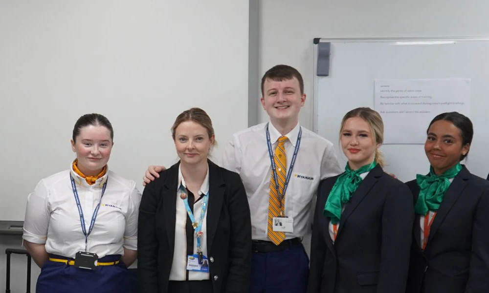 Two Travel and Tourism alumni standing next to tutor and students