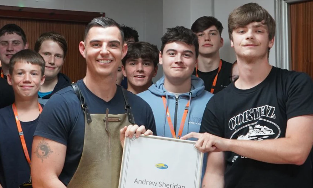 Chef Andrew Sheridan holding framed certificate while standing next to students