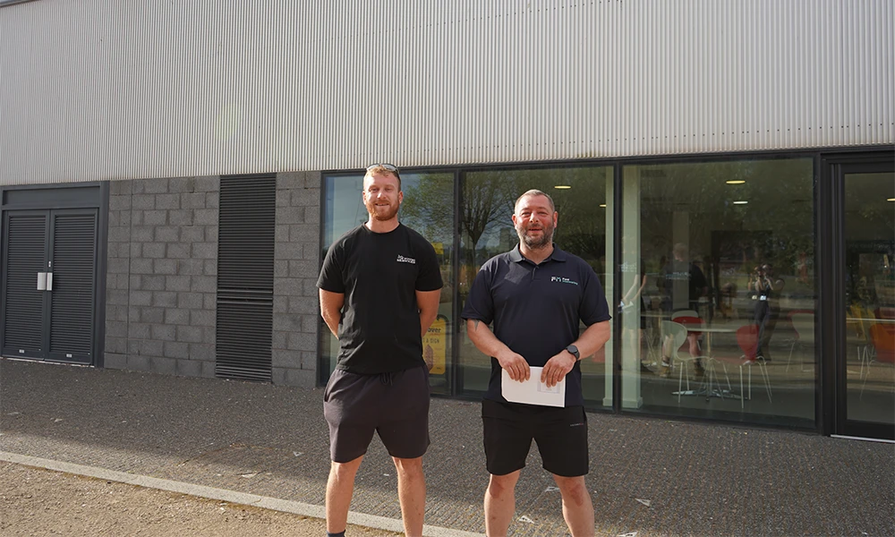 Two men standing outside Wirral Waters campus during BTEC Results day