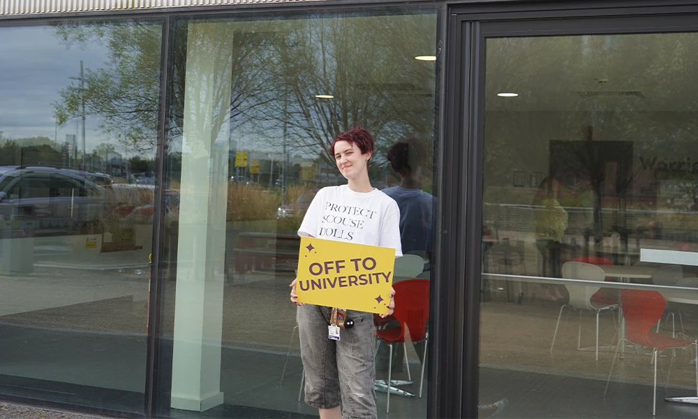 person holding an Off To University Sign whilst standing outside Wirral Waters during BTEC Results Day