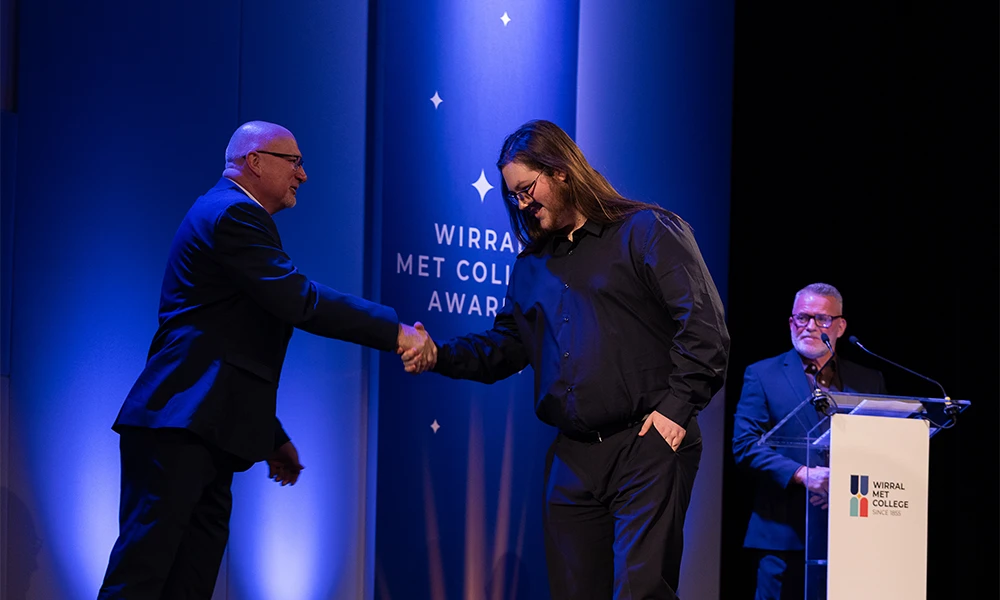 Male student shaking hands with tutor on stage