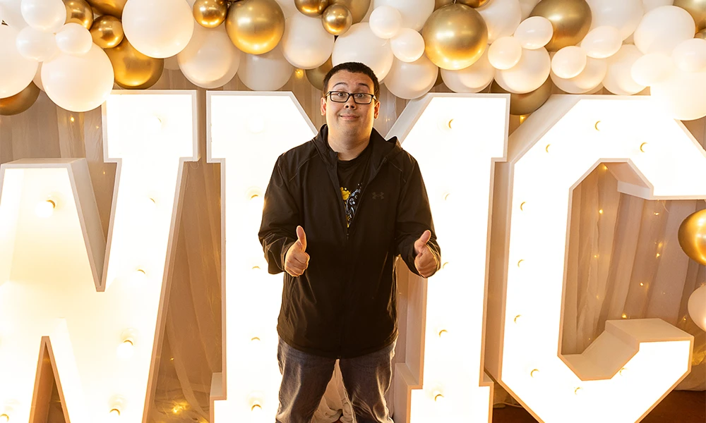 Male student posing for his picture in front of bright Wirral Met sign
