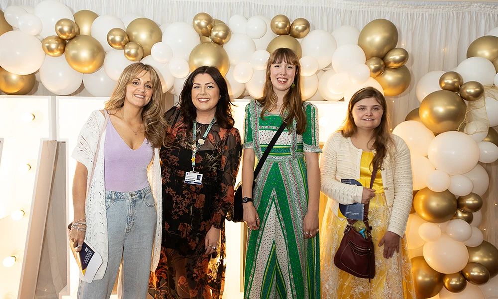 Group of students standing next to tutor in front of bright Wirral Met sign
