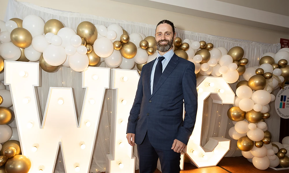 Man dressed in a suit standing in front of bright Wirral Met sign