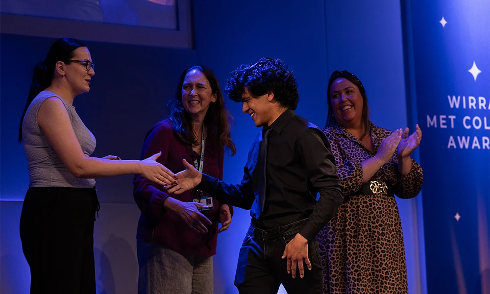 male student shaking hands with tutors as he crosses the stage