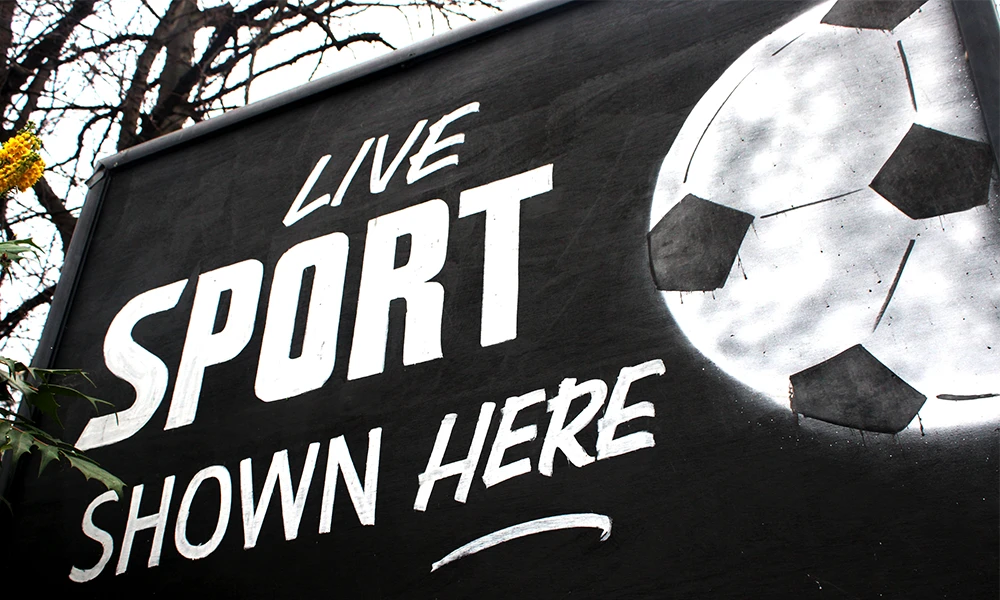 A black and white sign with Live Sport Shown Here written