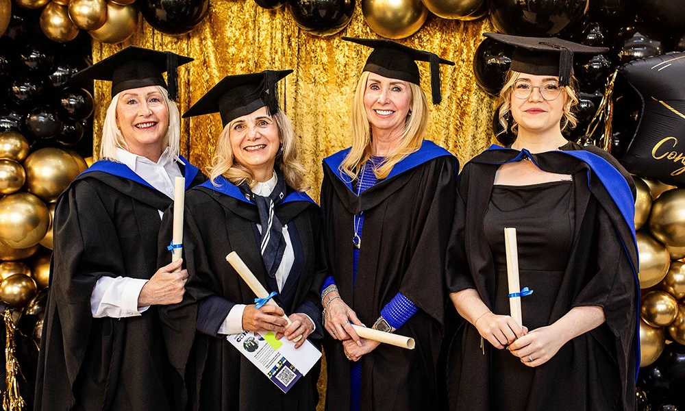 4 Women in cap and gown smilling at the camera